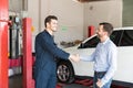 Customer Shaking Hands With Car Mechanic At Repair Shop