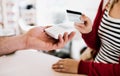 Customer and shop assistant making contactless payment using credit card in a shop. Royalty Free Stock Photo