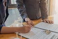 Customer signing a paper document for buying house. Estate agent pointing finger showing where to sign on wooden desk. Real estate