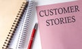 CUSTOMER STORIES word on the pink paper with office tools on white background