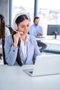 Customer support agent woman in headset with microphone talking to client and using laptop at call center. Royalty Free Stock Photo