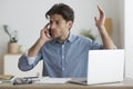 Businessman Complaining About Laptop Problems By Cellphone Sitting In Office