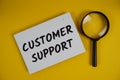 Customer Support letters with magnifying glass flat lay on yellow background Royalty Free Stock Photo