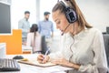 Customer support operator woman talking to a client and writing notes to notebook in call center. Royalty Free Stock Photo