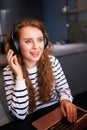 Customer support service call center manager speaking, working from home. Curly woman with headset enjoys listening to