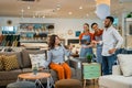 customer tries to sit on a sofa while two waiters serve customers