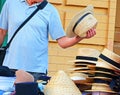A customer is trying on a hat with a headband. Man trying on a straw hat. Selling hats on the street Royalty Free Stock Photo