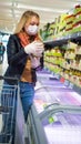 customer wearing facial protective mask buying and choosing, reads information on a label. Purchase of food during the