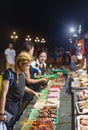 Customers choose from trays of barbecue food for sale,at night,along Rizal Boulevard