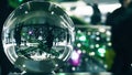 Unrecognizable customers in Christmas and New Year decorated shopping mall. Distorted view through the glass globe Royalty Free Stock Photo