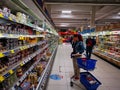 Customers at dairy and cheese shelves in supermarket Carrefour