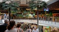 Customers On An Escalator Under Tropical Shopping Centre Decor