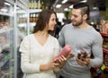 Customers near fridge with meat products Royalty Free Stock Photo