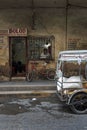 Customers wait at an old jewelry repair shop, with a tuk-tuk in front of the shop in Tabaco, the Philippines