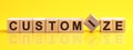 Customize word is made of wooden building blocks lying on the yellow table, concept