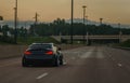 Customized and lowered import sportscar on open highway at dusk