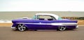 Customized Purple American vintage car on seafront promenade, sea and beach in background. .