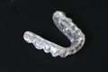 Customized transparent teeth bite guard clear aligners for lower jaw on black background Royalty Free Stock Photo