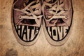 Customized used sneakers with words hate and love on grunge texture background Royalty Free Stock Photo