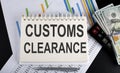 Customs Clearance text written on a notebook with chart,calculator and dollars Royalty Free Stock Photo
