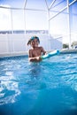 Cut African American little boy shooting a water gun while playing with friends in a backyard swimming pool. Royalty Free Stock Photo