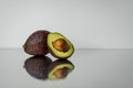 Cut avocado with bone, close-up on mirror background