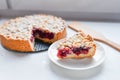 cut berry pie. slice of homemade sour cherry pie on plate and whole tart cut in slices in baking dish on napkin on wooden table, Royalty Free Stock Photo