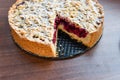 cut berry pie. slice of homemade sour cherry pie on plate and whole tart cut in slices in baking dish on napkin on wooden table, Royalty Free Stock Photo