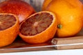 Cut blood oranges isolated on a wooden board with a knife