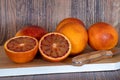 Cut blood oranges isolated on a wooden board with a knife