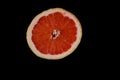 Cut bright red orange half grapefruit slice on black backdrop Royalty Free Stock Photo