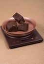 Cut and broken pieces of dark chocolate on the kitchen electronic scales Royalty Free Stock Photo