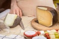 Cut cheese heads on the market counter, woman hands of seller with knife Royalty Free Stock Photo