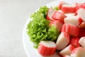 Cut crab sticks and lettuce on light table, closeup Royalty Free Stock Photo