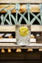 A cut crystal glass with cold water and a slice of lemon for drinks outdoors on a wooden bench