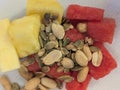 Cut into cubes of watermelon and pineapple with pumpkin seeds and peanuts sprinkled on a white plate Royalty Free Stock Photo