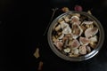 Cut fresh forest champignon mushrooms in a metallic bowl standing on black wooden table with some dry autumn leaves around it. Royalty Free Stock Photo