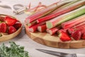 Cut fresh rhubarb stalks, strawberries and knife on white wooden table, closeup Royalty Free Stock Photo