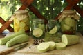 Cut fresh zucchini and jars of pickled vegetables on white wooden table