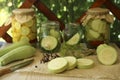 Cut fresh zucchini and jars of pickled vegetables on white wooden table