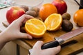 Cut fruit with a knife. Ripe oranges and knife on a wooden board. Sliced orange, kiwi and apples on the table. Royalty Free Stock Photo