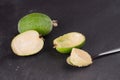 Cut fruit of the mature feijoa on a dark slate background. Pulp fruit on the bark spoon Royalty Free Stock Photo