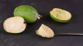 Cut fruit of the mature feijoa on a dark slate background. Pulp fruit on the bark spoon Royalty Free Stock Photo