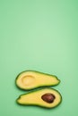 Cut in half avocado isolated on green background. Top view. Copy space. Creative concept