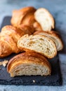 Cut in half croissant with inside texture and thin crisp layers on black board, grey background. Delicious french pastry