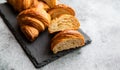 Cut in half croissant with inside texture and thin crisp layers on stone board, grey background. Delicious french pastry