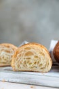 Cut in half croissant with inside texture and thin crisp layers on wooden board, light concrete background. Delicious french