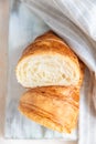 Cut in half croissant with inside texture and thin crisp layers on wooden board, light concrete background. Delicious french