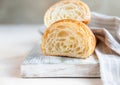 Cut in half croissant with inside texture and thin crisp layers on wooden board, light concrete background. Delicious french