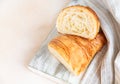 Cut in half croissant with inside texture and thin crisp layers on wooden board, light concrete background. Delicious french